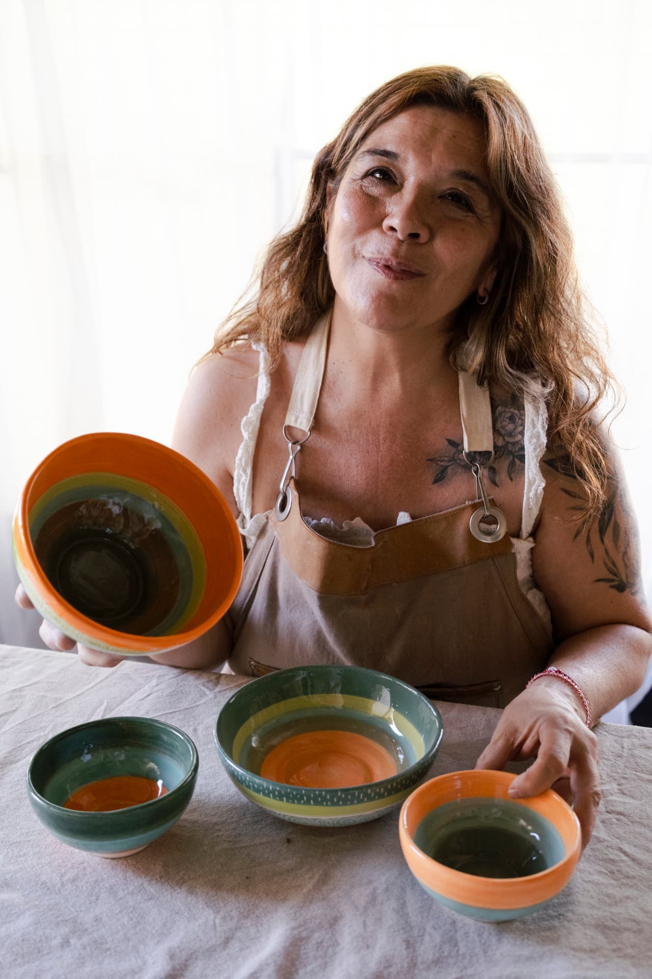 Ceci Barrionuevo con un juego de cuencos de cerámica de autor UGA en tonos verdes y naranjas