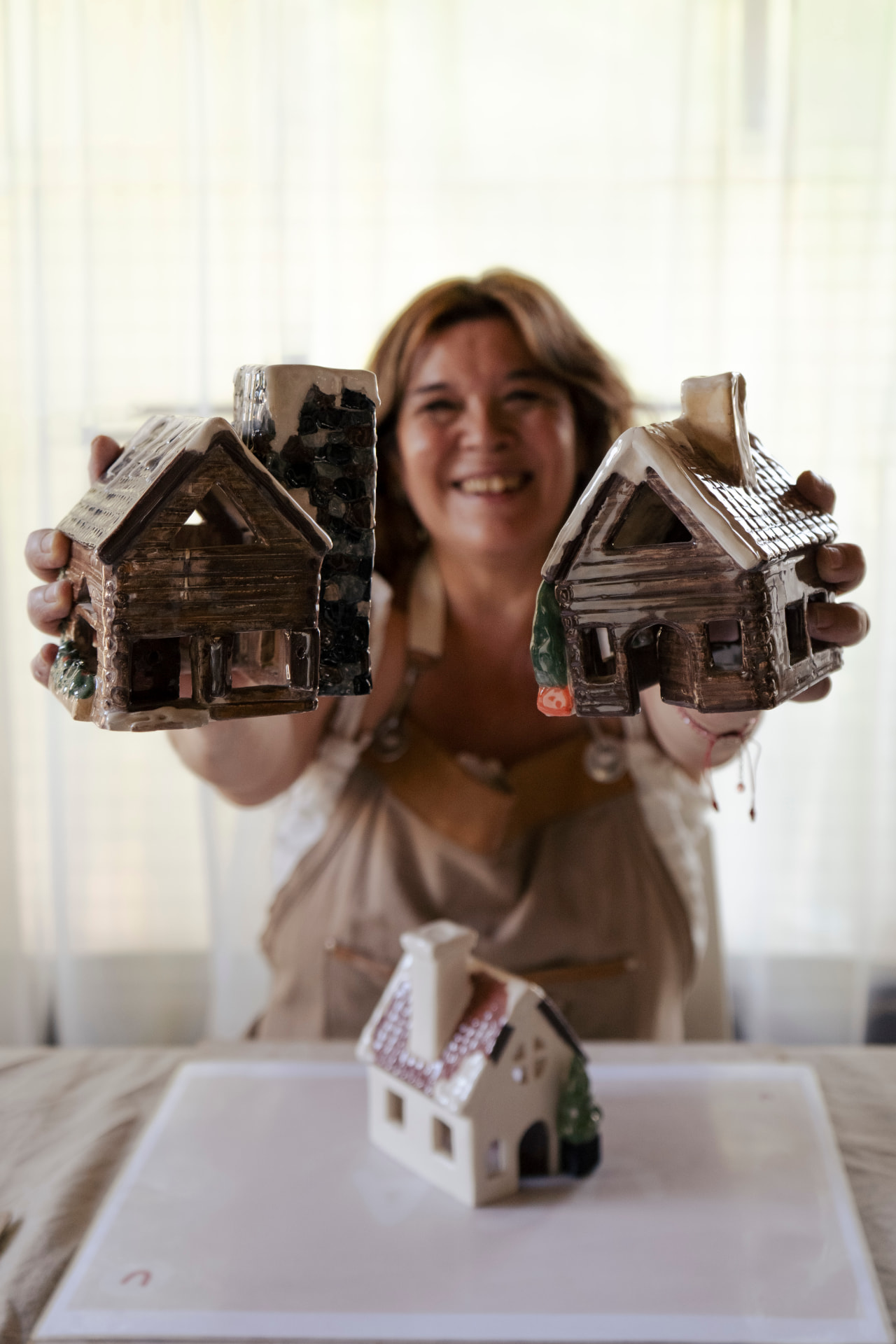 Ceci sosteniendo dos casitas de cerámica UGA